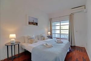a white bedroom with a bed and a window at Falésia Sunny Apartment in Quarteira