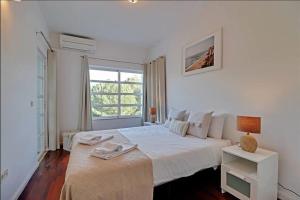 a white bedroom with a large bed and a window at Falésia Sunny Apartment in Quarteira