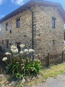a stone house with a fence in front of it at Casita feliz entre montañas y cerca del mar in Trabada