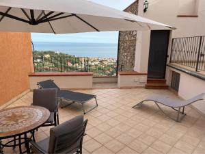 patio con tavolo, sedie e ombrellone di Maison Paradiso: Charme e relax a Pietra Ligure a Pietra Ligure