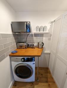 a small kitchen with a washing machine and a microwave at Arawak in Kent