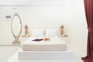 a white bedroom with a bed and a mirror at Hotel Sunshine Matala in Matala
