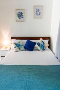 a bedroom with a white bed with blue pillows at Amara Family 2Br House, pool, 180Mbps, garden , parking Central location in General Luna