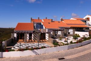 a house with orange tiled roofs on a street at Falésias da Arrifana in Praia da Arrifana