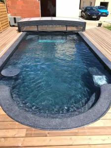 una grande piscina d'acqua con terrazza in legno di Villa Katharos avec SPA et piscine a Vesly