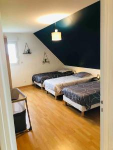 Zimmer mit 3 Betten und einer schwarzen Wand in der Unterkunft Villa Katharos avec SPA et piscine in Vesly