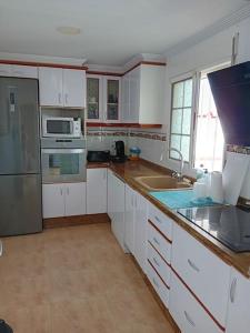 eine Küche mit weißen Schränken und Küchengeräten aus Edelstahl in der Unterkunft Casa de Verano con Piscina in Montroy