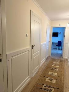 korytarz z białymi drzwiami i dywanem w obiekcie Go Mazury w mieście Mrągowo