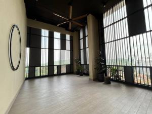 Societe Suites Hartamas في كوالالمبور: غرفة كبيرة بها نوافذ كبيرة ونباتات