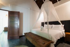 スミニャックにあるThe Gardens Seminyakのベッドルーム1室(天蓋付きベッド1台、木製ベンチ付) +30枚の写真