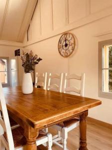 Un comedor con una mesa de madera y un reloj en la pared. en Beach House by Melrose, en Asnelles