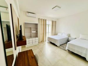 Biała sypialnia z 2 łóżkami i telewizorem w obiekcie Apartamento alto padrão na Doca w mieście Belém