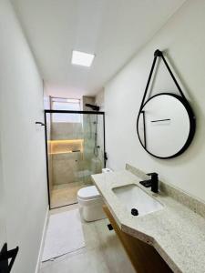 W łazience znajduje się umywalka, toaleta i lustro. w obiekcie Apartamento alto padrão na Doca w mieście Belém