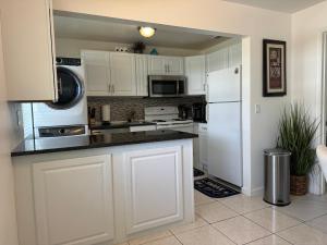 cocina con armarios blancos y nevera blanca en Cozy 2 bedroom near intercoastal & beaches, en North Palm Beach