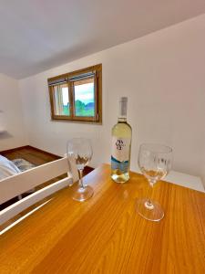 博薩的住宿－Casa del Mare Guest house，木桌旁的一瓶葡萄酒和两杯酒