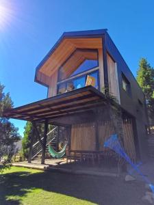 une maison avec un hamac en face de celle-ci dans l'établissement Casa de montaña La Cumba Patagonia., à San Martín de los Andes