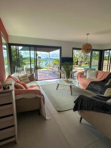 uma sala de estar com um sofá e uma mesa em Grande Villa Familiale avec piscine et Accès Privé à la Plage em Païta