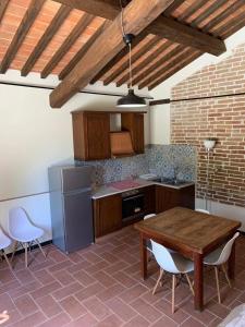 a kitchen with a wooden table and white chairs at Agriturismo Diffuso Monte Oliveto Maggiore in Chiusure