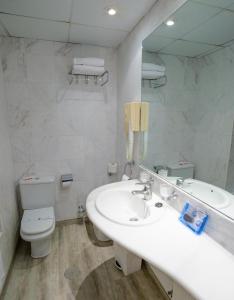 a bathroom with a sink and a toilet and a mirror at Hotel Avenida in Benidorm