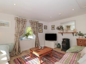 ein Wohnzimmer mit einem Sofa, einem TV und einem Tisch in der Unterkunft The Croft Retreat in Bridgwater