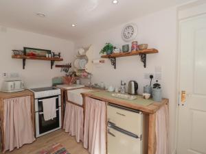 a kitchen with pink curtains on the counters at The Croft Retreat in Bridgwater