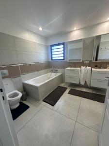 a bathroom with a tub and a toilet and a sink at Grande Villa Familiale avec piscine et Accès Privé à la Plage in Païta