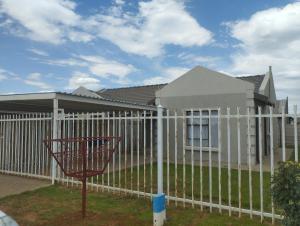 a white fence in front of a house at Eden Guest Farm in Bloemfontein