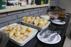 a counter with three trays of food on it at Premier Hotel in Votuporanga +10 photos