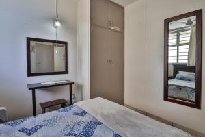 een slaapkamer met een bed, een spiegel en een tafel bij Beach Bliss in Amanzimtoti