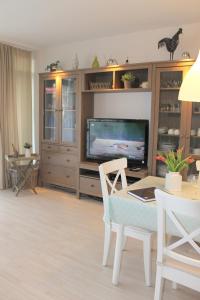 een woonkamer met een televisie en een tafel en stoelen bij Haus Baltic - Whg 23 - NEU inkl Saisonstrandkorb! in Grömitz