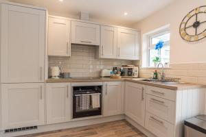 a kitchen with white cabinets and a clock on the wall at Larkswood Annex in Bradpole