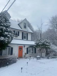 a house with an orange door in the snow at Elegantly English Catskills in Liberty