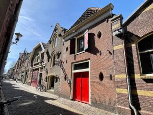 ein Backsteingebäude mit einer roten Tür auf einer Straße in der Unterkunft Grapèlli Boutique Hotel in Alkmaar