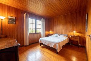 Schlafzimmer mit einem Bett, einem Fenster und Holzwänden in der Unterkunft Chalet de Charme avec vue spendide in Menthon-Saint-Bernard