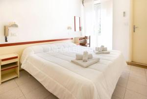 duas camas num quarto com lençóis brancos e toalhas em Due Gemelle em Rimini
