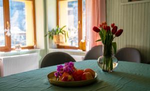 un plato de fruta y un jarrón de flores sobre una mesa en Гагинската къща, en Martinovo
