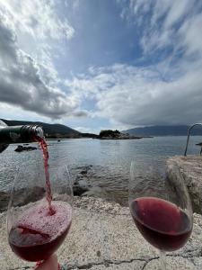 una persona che versa vino rosso in un bicchiere di vino di Bay House Kakrc a Tivat