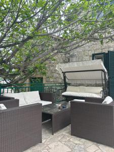 um pátio com mobiliário de vime e uma árvore em Bay House Kakrc em Tivat