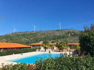 a swimming pool in front of a mountain with windmills at Gojim Casa Rural in Armamar