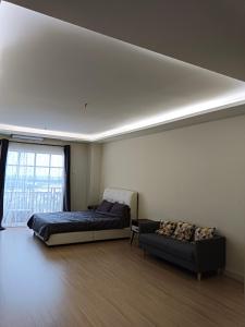 a bedroom with a bed and a couch and a window at Infinity homestay @ Champs Elysees kampar in Kampar