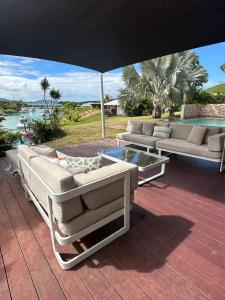 une terrasse avec des canapés, une table et un parasol dans l'établissement Grande Villa Familiale avec piscine et Accès Privé à la Plage, à Païta