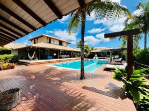 a swimming pool with a house and palm trees at Casa Canada Bahia in Praia do Espelho