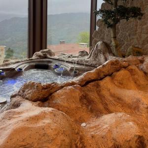 a hot tub with a large rocks in front of a window at Encosta de Louredo by Pousadela Village in Vieira do Minho