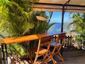 un tavolo in legno e sedie su una terrazza con vista di Sur La Mer - Appartement Deux chambres à Schoelcher a Schœlcher