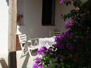 - une table, des chaises et des fleurs violettes sur la terrasse dans l'établissement Ferienhaus in Partinico mit Terrasse und Grill, à Balestrate