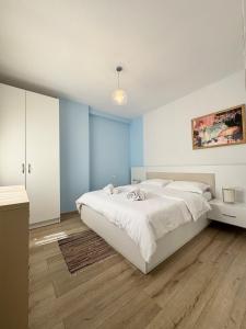 - une chambre avec un lit blanc et des murs bleus dans l'établissement Apartment in the New Bazaar of Tirana - Hana Blu, à Tirana