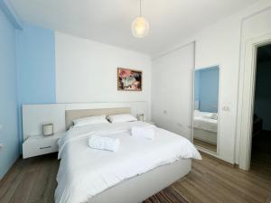 - une chambre blanche avec un grand lit et un miroir dans l'établissement Apartment in the New Bazaar of Tirana - Hana Blu, à Tirana