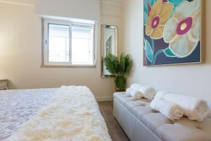 a bedroom with a bed and a couch with towels at beachome4u4 / Carcavelos beach in Parede