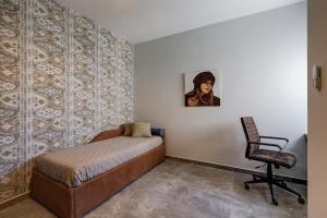 ein Schlafzimmer mit einem Bett, einem Stuhl und einem Gemälde in der Unterkunft Lovely Penthouse In Mellieha-seaview in Mellieħa