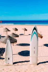two surfboards in the sand on a beach with umbrellas at beachome4u4 / Carcavelos beach in Parede